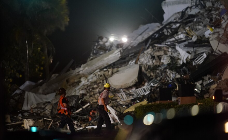 Rescue workers walk beside the rubble as rescue efforts continued on Thursday night.