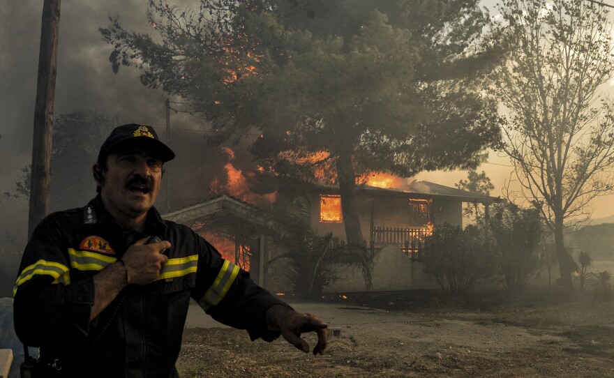 A firefighter next to a house burning during a wildfire in Kineta, near Athens, Greece, on Monday. Wildfires are not new to Greece but several blazes erupted especially quickly.
