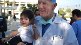 Pediatric heart surgeon Dr. Leonard Bailey holds one of his patients, David Escarcega, featured in the film "The Adventists."