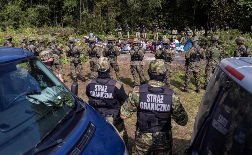 Polish border guards stand near a group of migrants believed to be from Afghanistan in the small village of Usnarz Gorny near Bialystok, northeastern Poland, located close to the border with Belarus, in August.