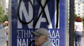 A man waits at an Athens bus stop where the Greek word "yes" has been spray-painted over "no" on a banner put up in advance of Sunday's referendum. Greek voters will say whether they want to accept or reject a deal that's been offered by the country's creditors. Greeks are deeply divided and analysts say the outcome is not clear. 