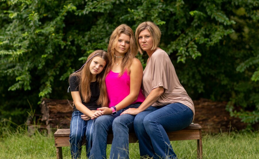 Allie Henderson with her sister Claire (left) and her mom, LeAnn, outside their home recently in Terry, Miss. "I want people to get vaccinated — because I know what it feels like," Allie says of her near-fatal encounter with COVID-19 this year.