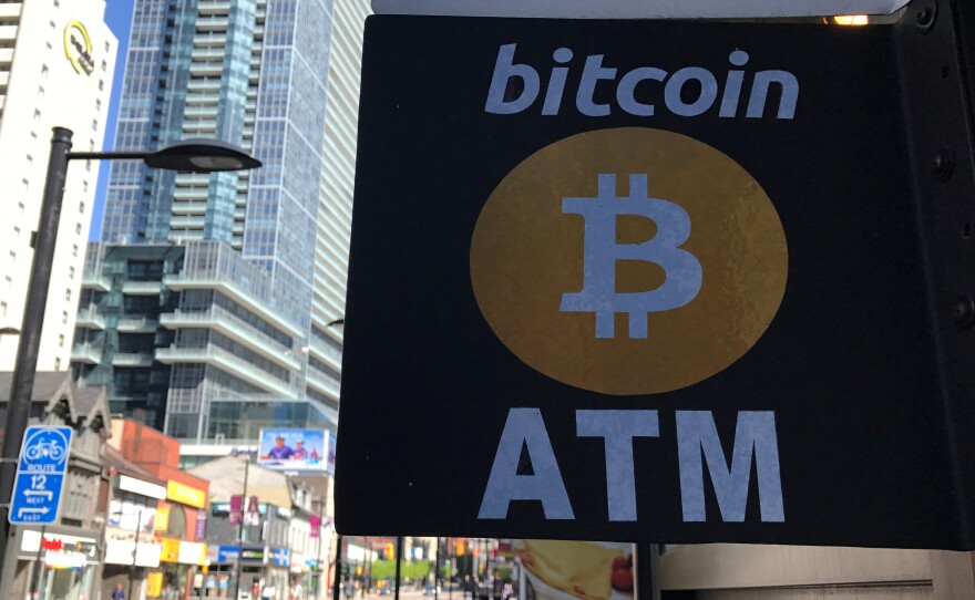 Led by a drop in bitcoin's price, the value of cryptocurrencies fell by more than $40 billion over the weekend and into Monday. Here, a sign advertises a Bitcoin ATM in Toronto, Canada, last summer.