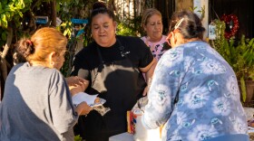 Isa Rosales (center) hands a plate of hot food to a neighbor in Shelltown on Wednesday, April 3, 2024.