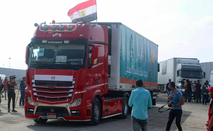 People on the Egyptian side of the Rafah border crossing watch as a convoy of trucks carrying humanitarian aid crosses to the Gaza Strip on Sunday.