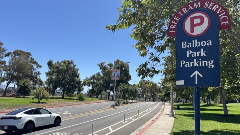 A car drives past a sign directing traffic to Balboa Park's parking lots and free tram service, July 28, 2025.