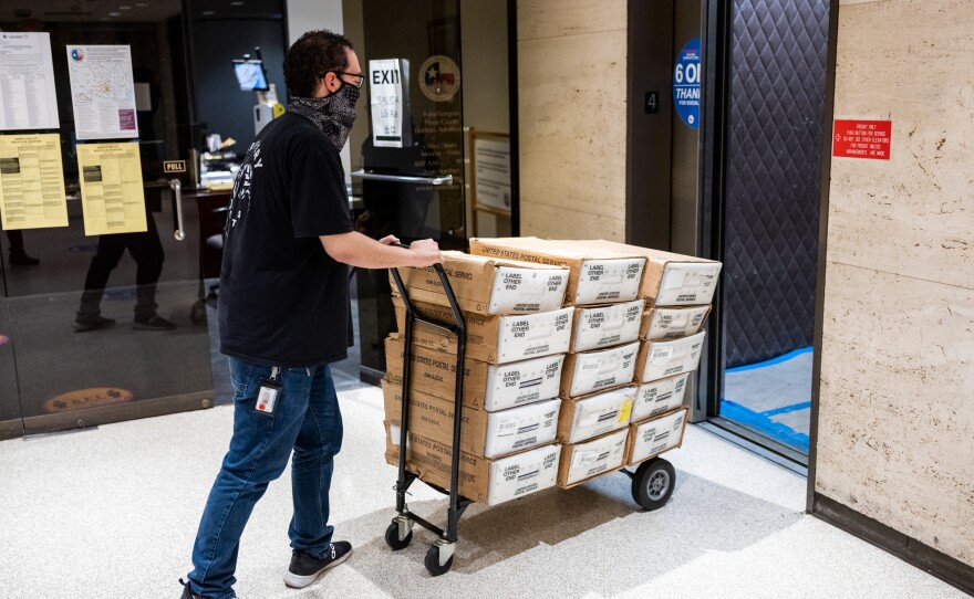 Carlos Vanegas pushes a cart with mail-in ballots that will be sent to voters at the Harris County Elections Office in Houston.