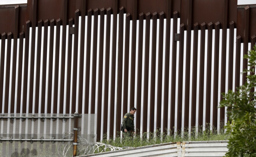 A Border Patrol agent walks along a border wall separating Tijuana, Mexico, from San Diego, in March 2020.