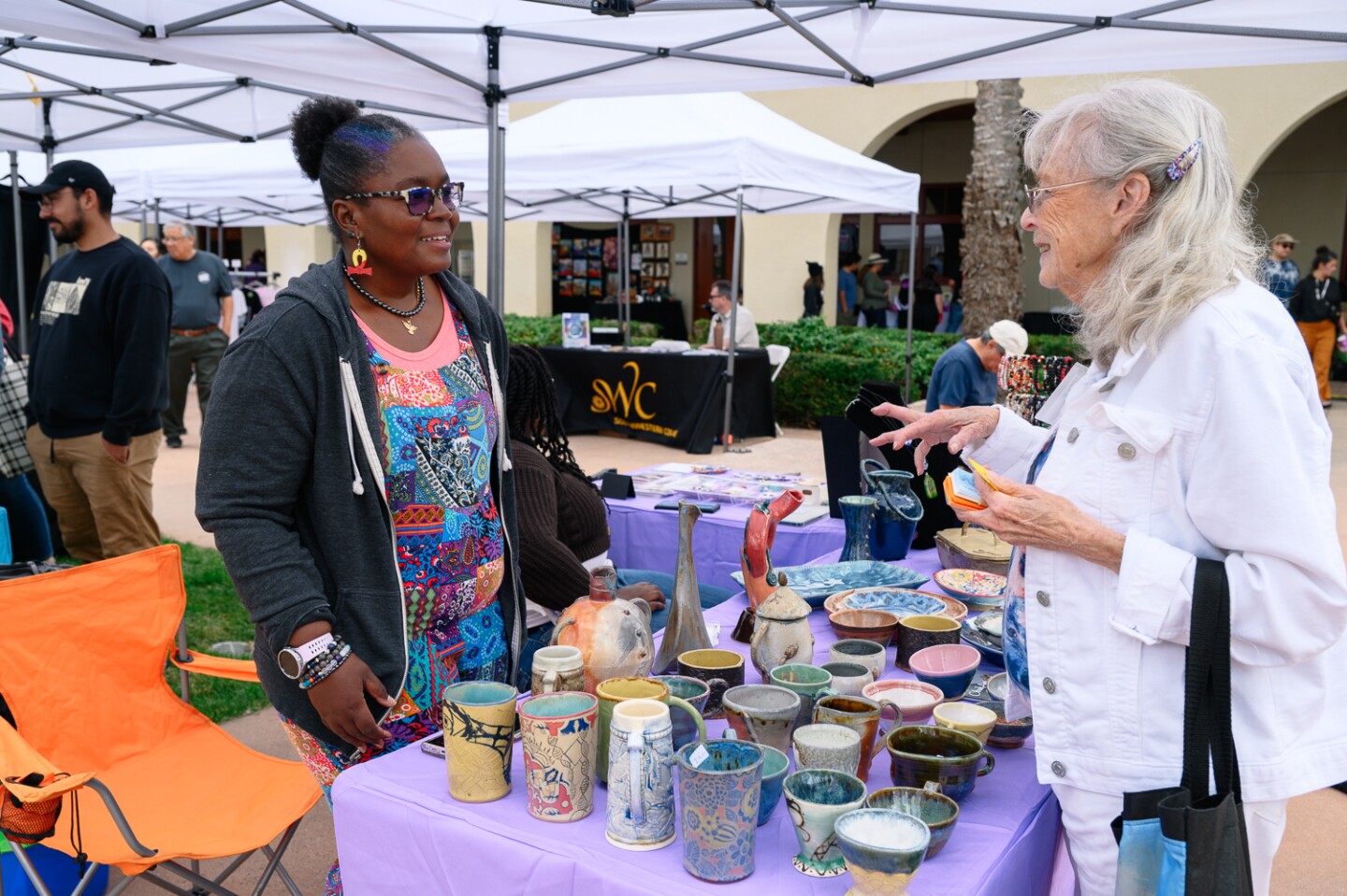 Ceramics and glasswork artist Kouassi Aragao, left, talks with a customer during the inaugural Chula Vista Art Fest, outside Chula Vista City Hall, on Sept. 30, 2023. Aragao was enjoying all of the festivities, especially the live music. “There is no art without music,” Aragao said.