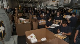 Sailors sort mail aboard the aircraft carrier USS Nimitz while conducting a replenishment-at-sea.