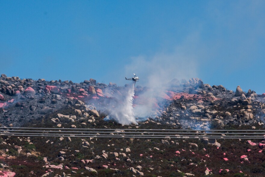 A helicopter drops water on the Coyote Fire in the Potrero community in South San Diego County, Aug. 18, 2023.