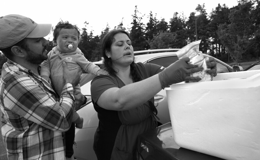 Cris Matocchi (left) holds Tabitha Sierra's youngest child on May 28, 2020. Matocchi and Sierra have been tasked with testing more than 3,000 people on the island.