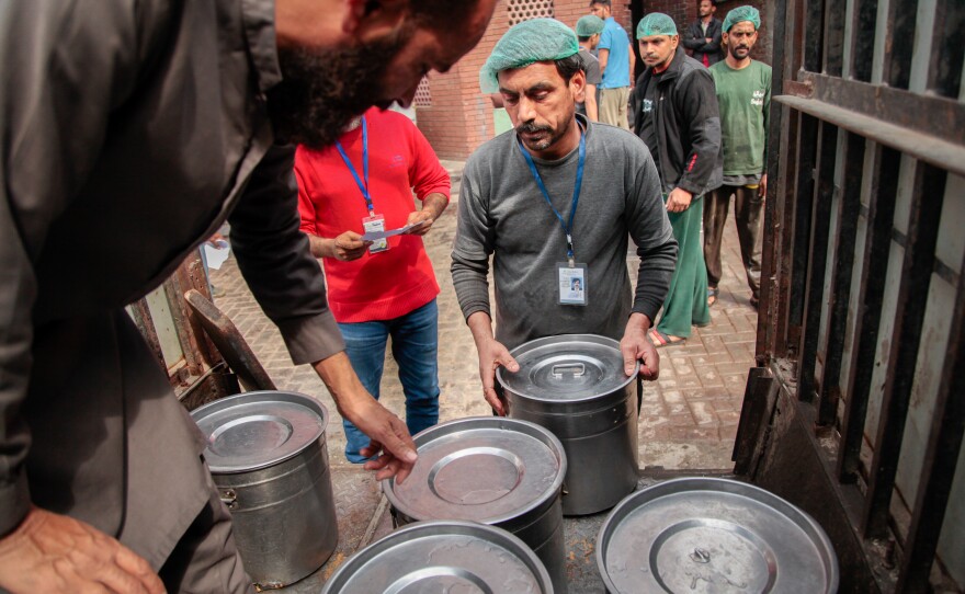 A worker at the Pakistani charity Saylani supervises the loading of vats of freshly cooked food into an open-backed jeep. The food will be distributed to 40 free cafeterias run by the charity in the city of Faisalabad.