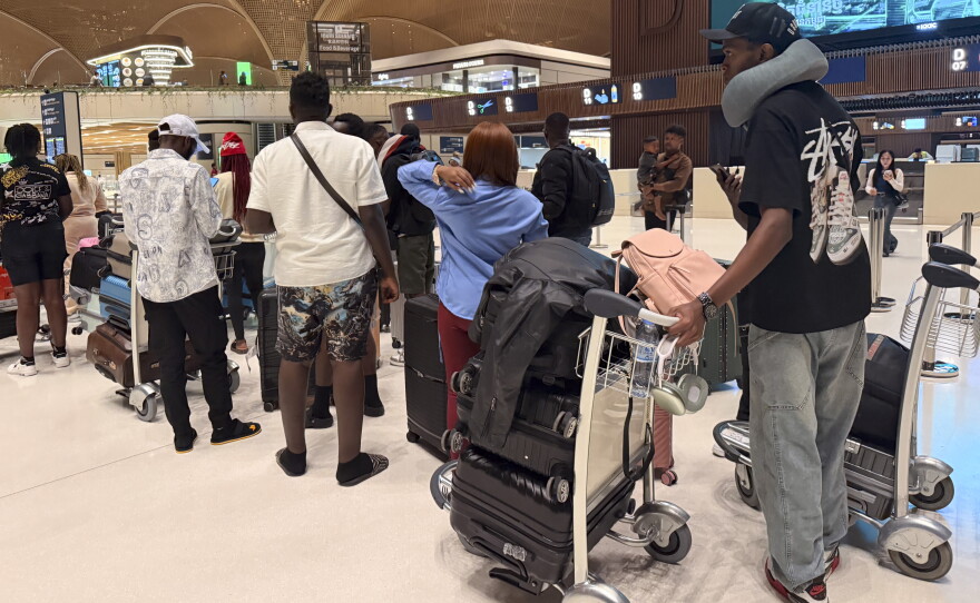 A group of Ugandan men and women line up to board their flight back home, after being released from scam compounds in Cambodia and then enduring compounding hardship on the streets of Phnom Penh.