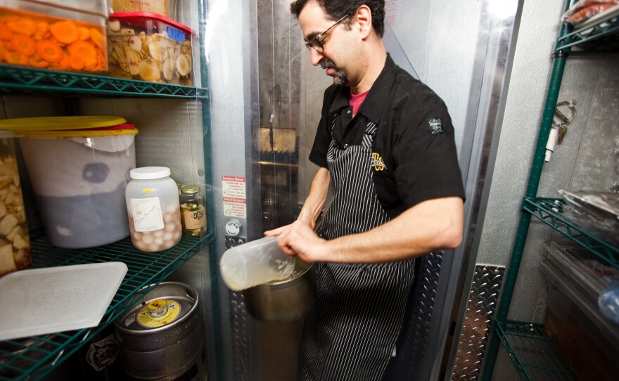 Barry Koslow, grabs ingredients from the walk-in refrigerator that houses all their pickled vegetables and smoked meat. "We'll pickle anything," he says.