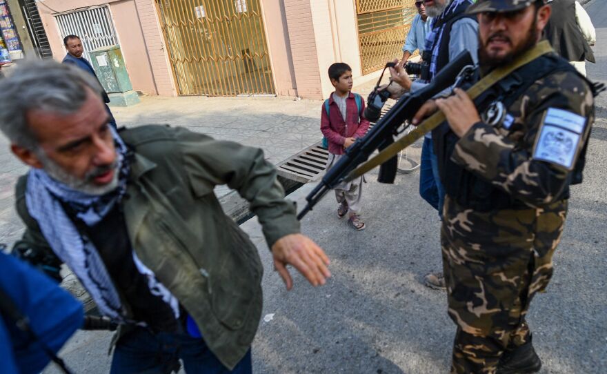 A member of the Taliban special forces pushes a journalist covering a demonstration by women protesters in Kabul on Sept. 30.
