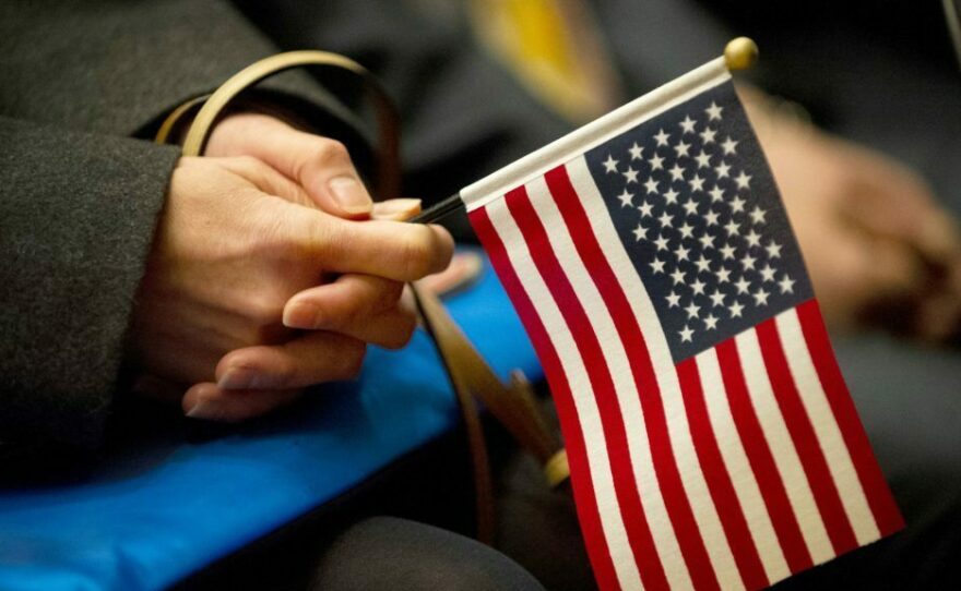 A woman holds a American flag during a naturalization ceremony.