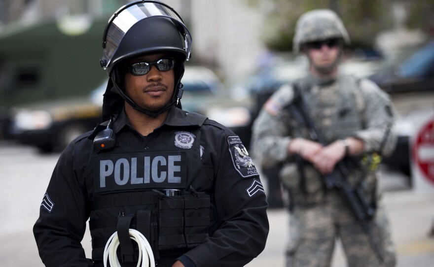 A National Guardsman and a police officer hold their positions at City Hall during a protest Wednesday in downtown Baltimore. Thousands marched, demanding justice for an African-American man who died of severe spinal injuries allegedly sustained in police custody, but most were off the streets shortly after the 10 p.m. curfew.