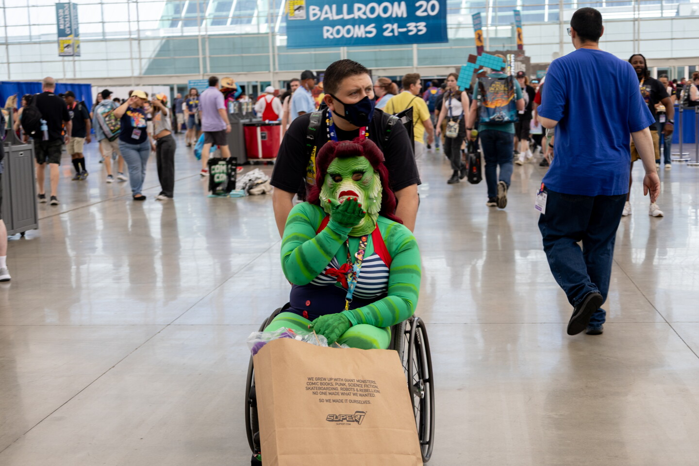 A Creature from the Black Lagoon cosplayer blows a kiss while being wheeled through the San Diego Convention Center during Comic-Con, July 24, 2026.