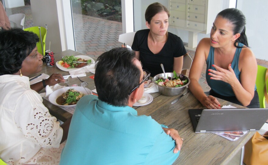 Miami swimwear entrepreneur Mel Valenzuela (right) explains online strategies to Cuban business owners Victor Rodriguez (middle) and Caridad Limonta (left) in Wynwood this month. Miami boutique owner Monica Minagorri (rear) watches.