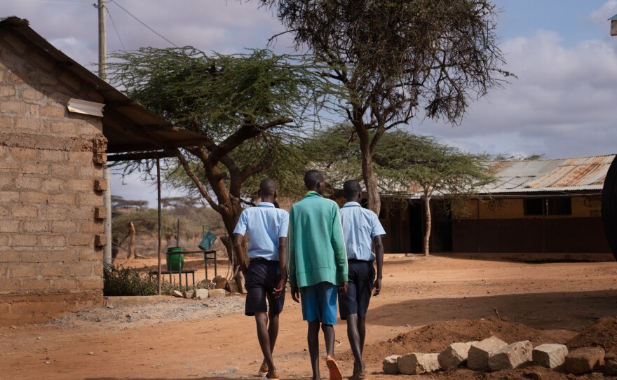 Paris (right) walks to class with fellow morans Saidimu Lolokile (left) and Loshaki Lekiliyo (center). Soon after Paris started at the elementary school, he convinced the others to join him. Now the three boys are inseparable.