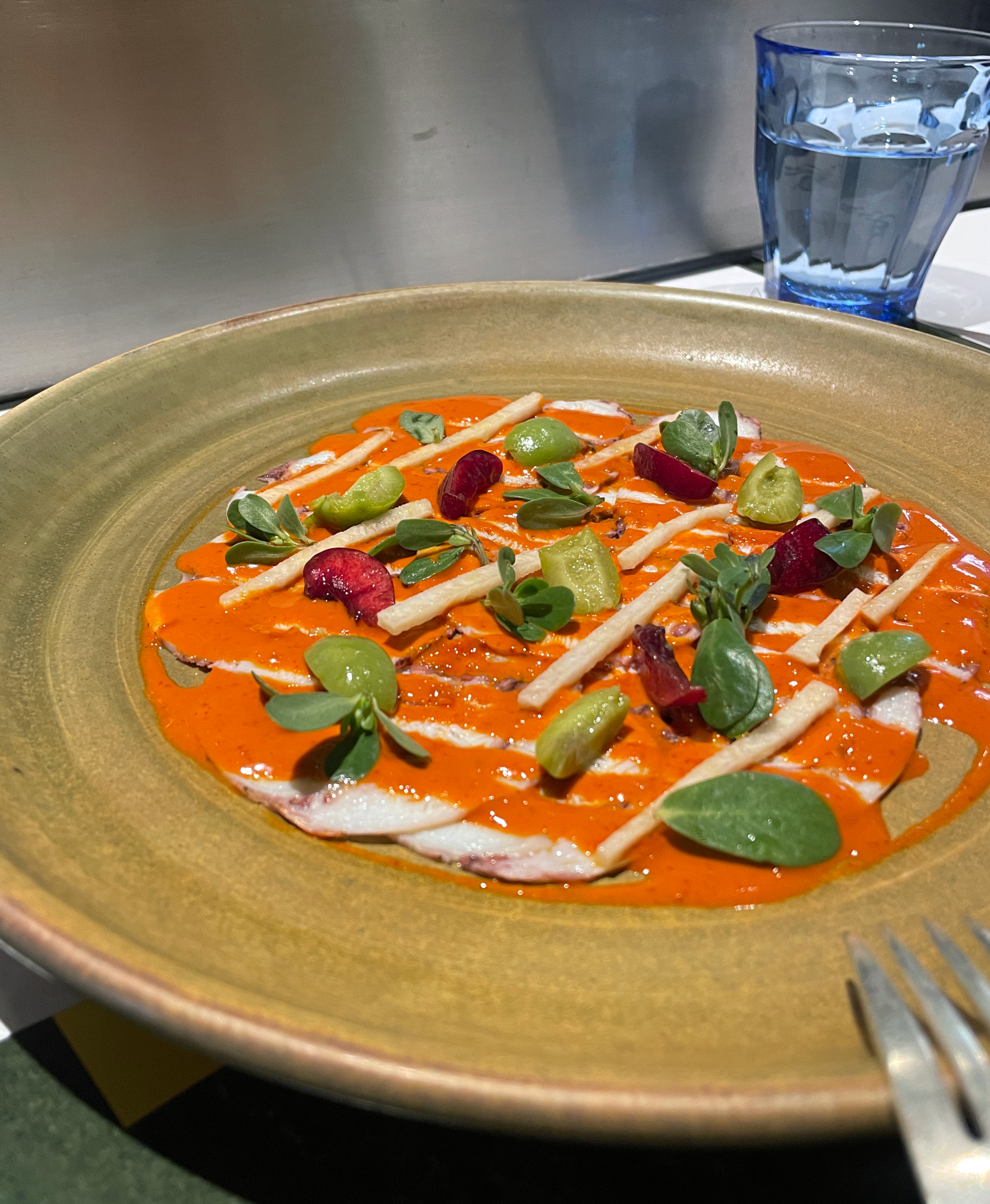 <b>Octopus Carpaccio</b><br/>Thin slices of octopus meticulously prepared and topped with a complex chili-lime dressing, Castelvetrano olives, jicama, cherries and local purslane — every bite flavorful and perfectly balanced.