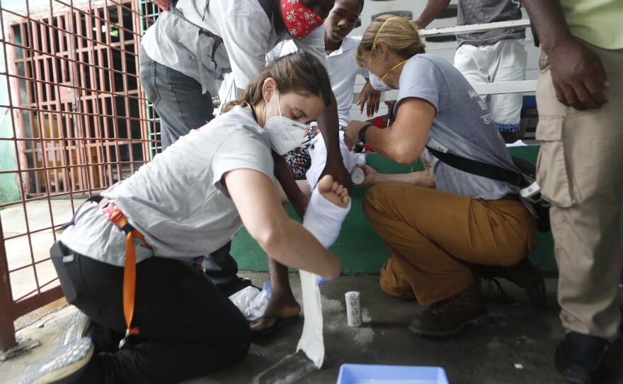 Drs. Maddie Ross and Heidi Haavik of Team Rubicon wrap a cast for Kendy Cazeau, 14, who sustained a broken leg in the earthquake.