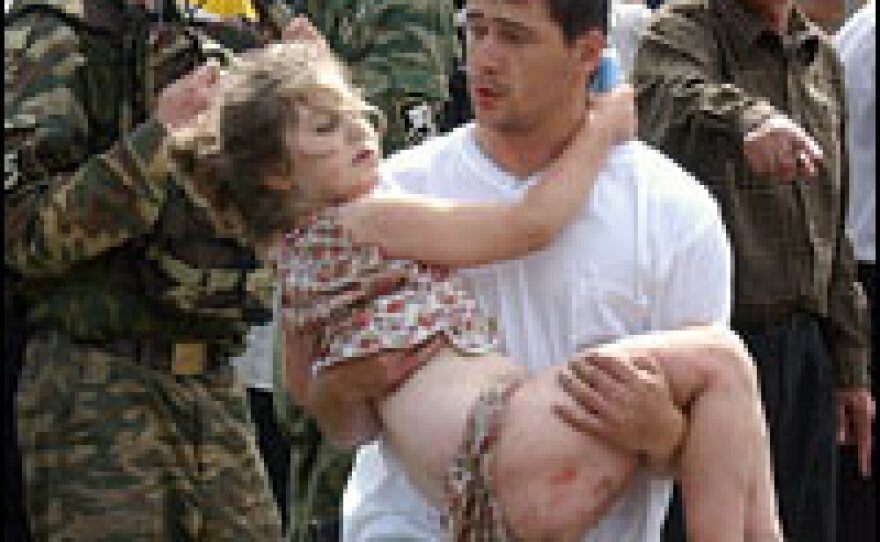 An Ossetian man carries a girl during a rescue operation at the Beslan School No. 1 on Sept. 3, 2004.
