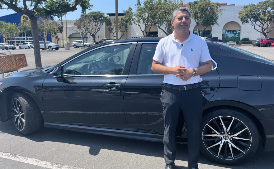 Rideshare driver and co-founder of San Diego Drivers United Librado Rivera stands next to his work car, Aug. 10, 2026.