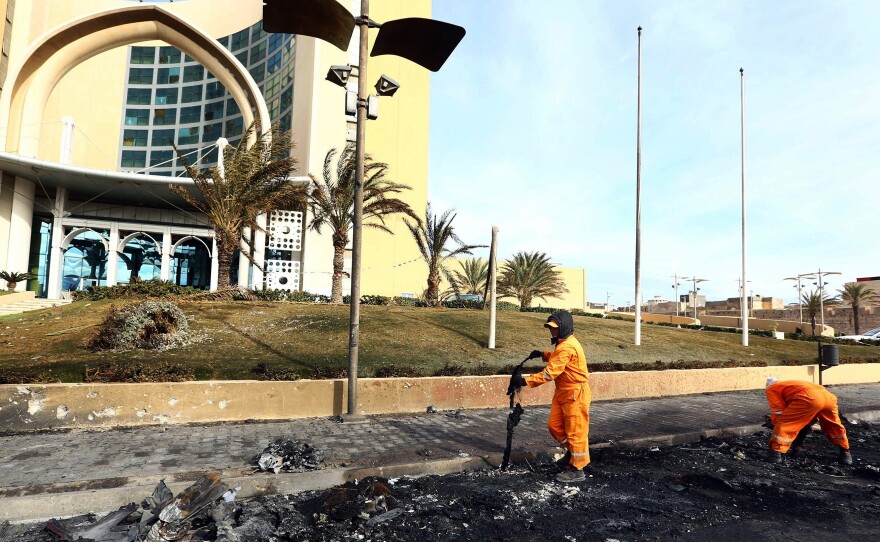 Workers clean the debris from the entrance of Tripoli's Corinthia Hotel, where gunmen blew themselves up after storming the hotel, killing at least nine people on Jan. 28. Multiple factions are fighting for control in Libya, which has two governments.