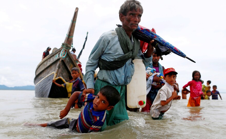 A Rohingya refugee pulls a child as they walk to shore after crossing the Bangladesh-Myanmar border by boat through the Bay of Bengal in Shah Porir Dwip, Bangladesh, on Sept. 10, 2017.