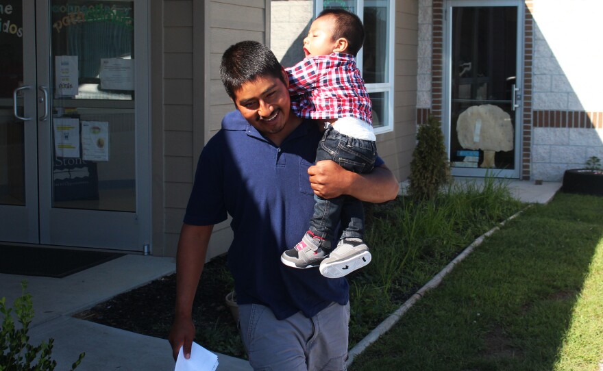 Martinez carries his toddler son, Richard, from the Head Start school building. The family spends about half the year in Florida, where there's work through the winter. That's the closest approximation of "home." The rest of the year, the children move from one school or preschool to another.