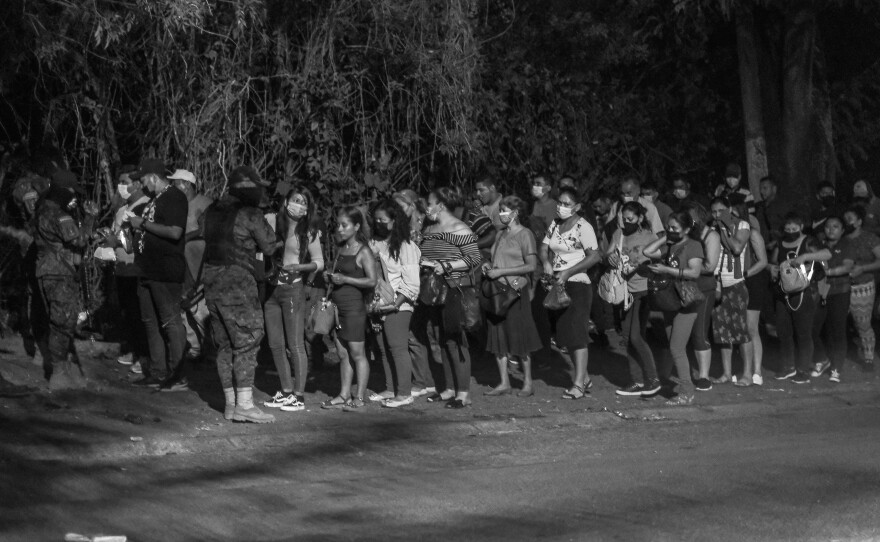 People line up to show their IDs to police at a checkpoint in Distrito Italia, a dangerous neighborhood in El Salvador, during the first days of the state of exception in April 2022.