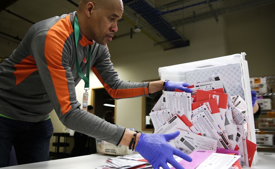 An election worker in Renton, Washington begins processing mail-in ballots during that state's presidential primary in March. Varying state-by-state requirements around signatures and other rules have become the focus of legal fights as absentee voting expands due to the pandemic.