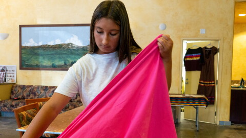Talia Boller holds the fabric of her ribbon skirt on July 21, 2026.