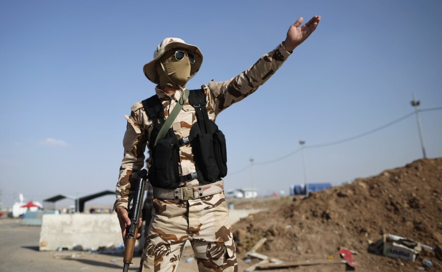 The Kurdish areas of northern Iraq have remained peaceful despite the recent surge in fighting. Here, a member of the Kurdish peshmerga forces directs traffic at a checkpoint in Kalak, in northern Iraq.