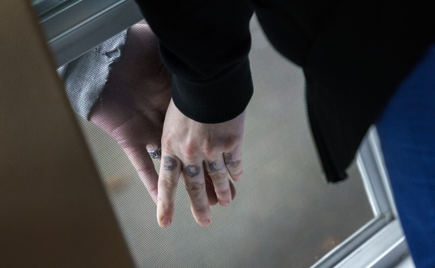 Unable to have visitors, Aleah and her boyfriend press their hands together, separated by the screen of an open window, as Aleah stays at Recovery Works Northwest's detox center.