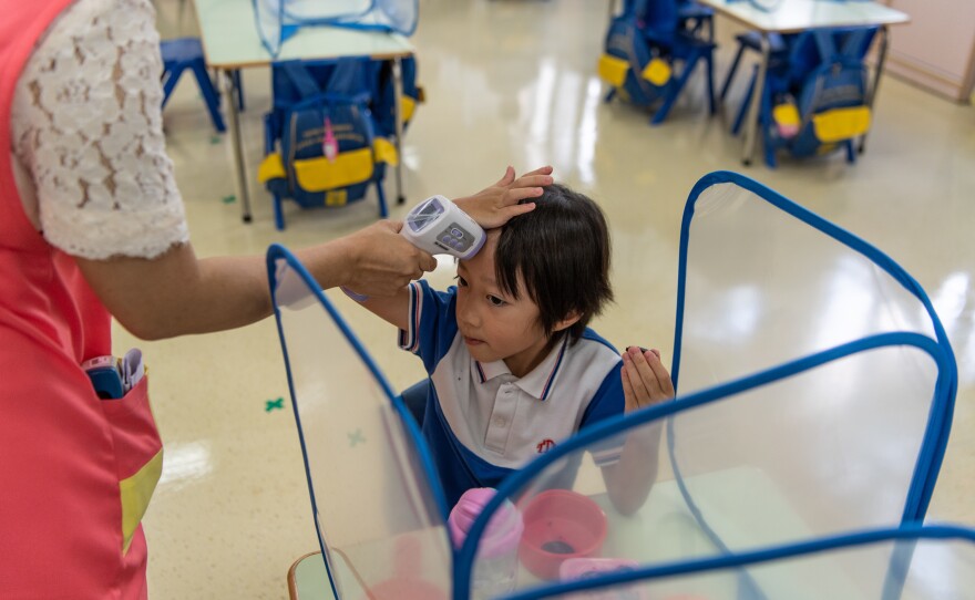 Students at Tsung Tsin Primary School and Kindergarten get their temperature checked.