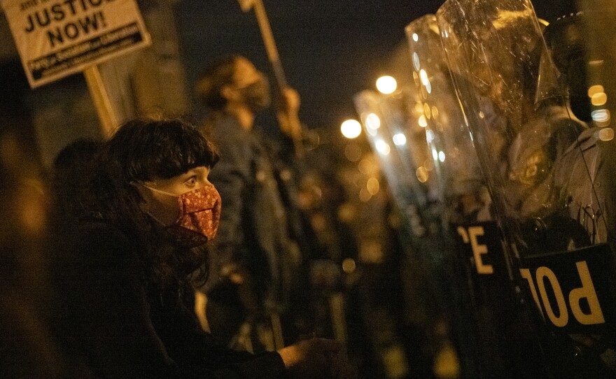 A demonstrator confronts police officers during a protest against the shooting of 27-year-old Walter Wallace.