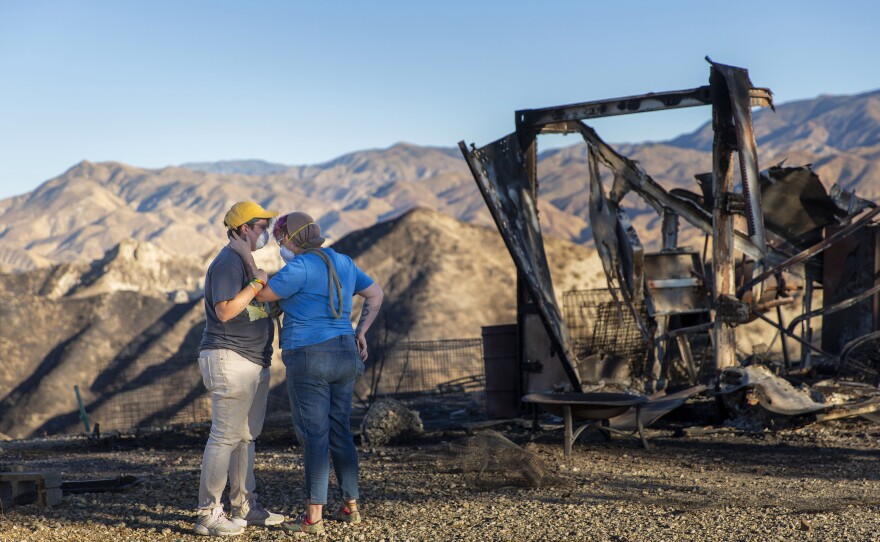 Lanthier and Hull pause for a moment while picking up some of their livestock that didn't make it out of the fire on Thursday. The two, who had about 80 animals, were able to rescue only 20 because of the fast-moving flames.