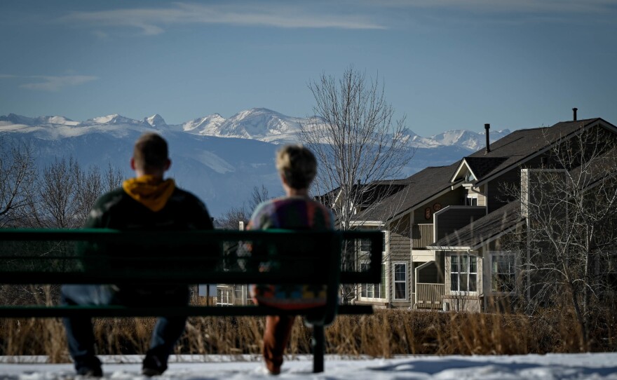 Two people sit in the foreground as Colorado's Rocky Mountains stand tall in the distance of Westminster, Colo., on Jan. 29.