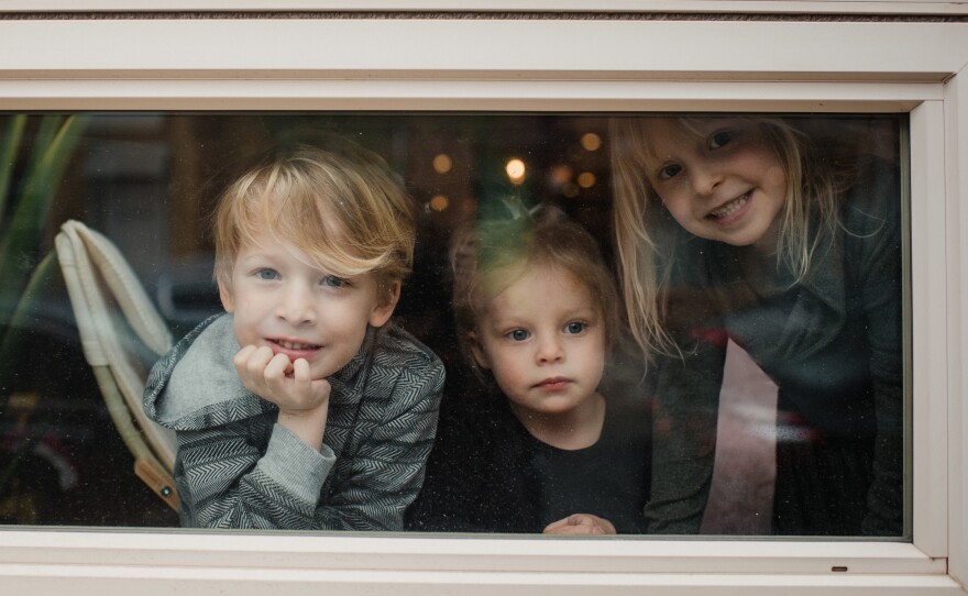 Matias McIntosh-Brix, 5, and his sisters Vivien, 2, and Nora, 5, play by the window at their home in Philadelphia on March 31. Parents Stacy Brix and Joel McIntosh both work in the health care industry and are alternating between their jobs and being at home with the kids.