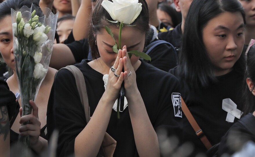 Mourners hold flowers Sunday and pray for a man who fell to his death after hanging a protest banner against an extradition bill in Hong Kong Sunday, June 16, 2019.