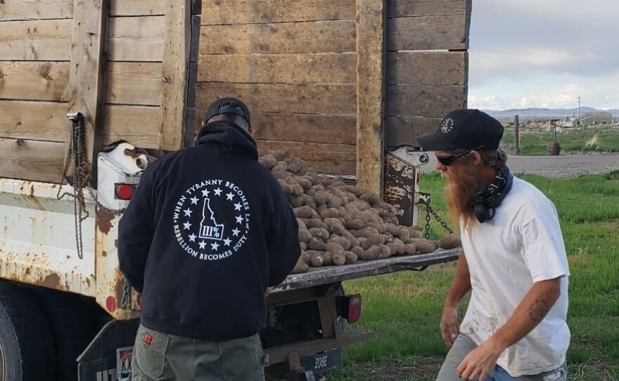 Members of the Real Idaho Three Percenters unload potatoes this week as part of a volunteer effort to give away crops that were unsold because of the coronavirus pandemic. Their activities raise questions about the role of militias in the pandemic response.