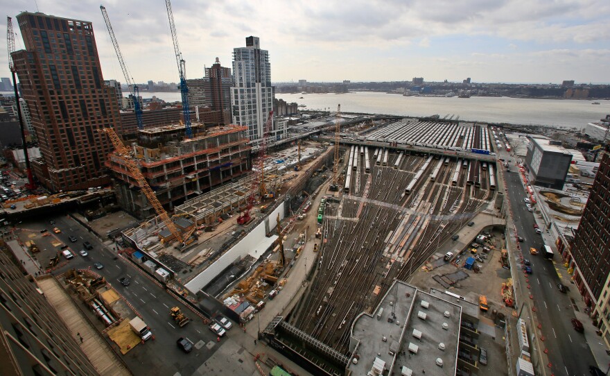 The Hudson Yards project site in 2014 shows ongoing construction of skyscrapers alongside parked Long Island Rail Road trains. A $20 billion undertaking, Hudson Yards will fill 28 acres between the Hudson River and 10th Avenue with 14 skyscrapers after completely covering the train yards with a platform foundation.