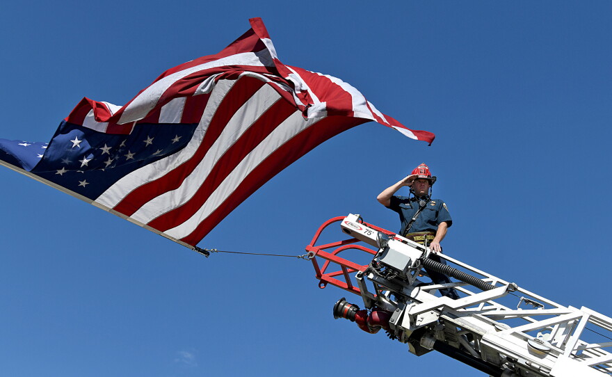 A captain with the Clifton Fire Protection District salutes the passing procession carrying the bodies of three firefighters killed while fighting the Snyder Fire in Grand Junction, Colo., on June 28.