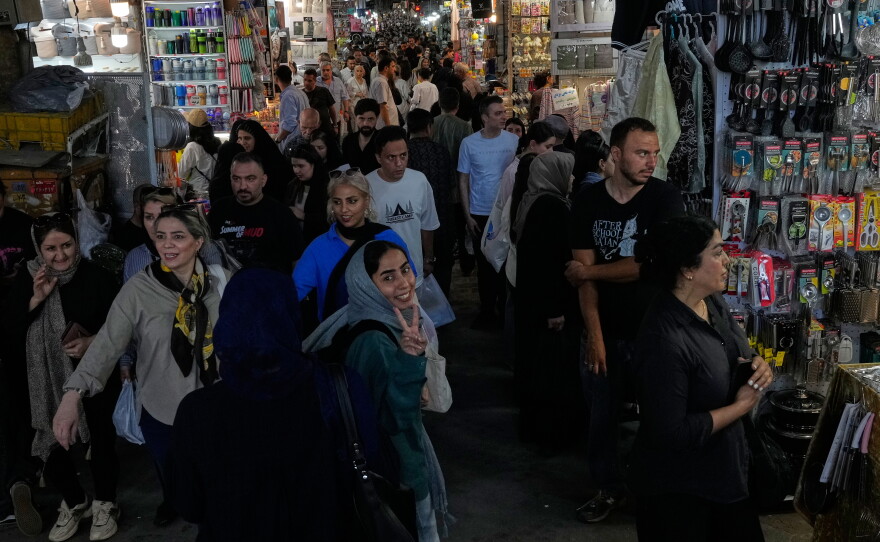 A woman flashes a victory sign while walking at Tehran's traditional main bazaar, Iran, Thursday, July 16, 2026.