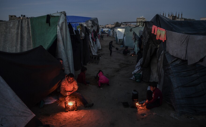 Palestinian families have been repeatedly displaced due to Israel's attacks on the Gaza Strip. Here a family living in a tent sits around a fire in Rafah, in southern Gaza, on Feb. 22.