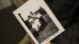 In this photo taken Tuesday, Feb. 11, 2020, Les Ouchida holds a 1943 photo of himself, front row, center, and his siblings taken at the internment camp his family was moved to, as he poses at the permanent exhibit titled "UpRooted Japanese Americans in World War II" at the California Museum in Sacramento, Calif. 