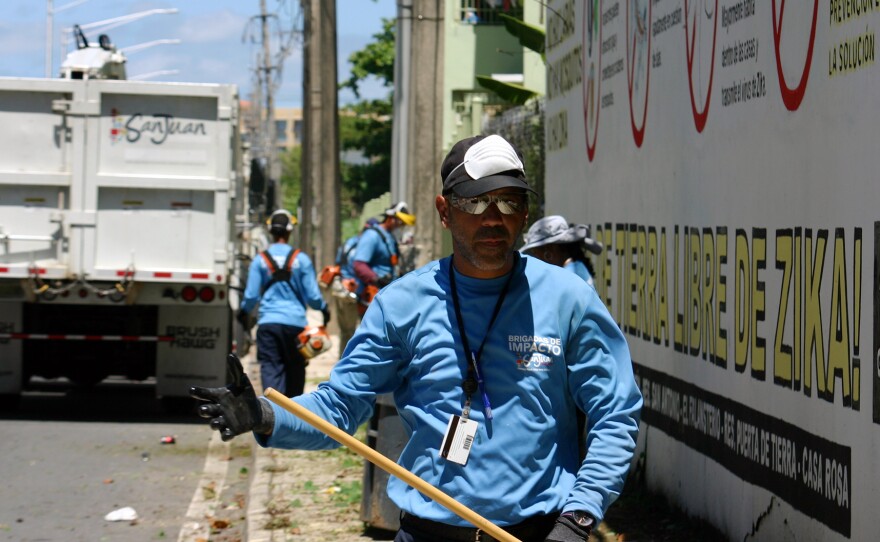 A city worker in San Juan, Puerto Rico cleans up a vacant lot where mosquitoes could be breeding.